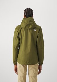 Oliivinvihreä tuulitakki hupulla, joustavilla hihansuuilla ja The North Face -logo yläselässä. Sileä, vedenpitävä kangas.