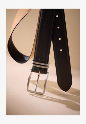 Črni usnjeni pas z gladko teksturo, z srebrno kovinsko sponko in več luknjami za prilagajanje. Dizajn je preprost in eleganten.