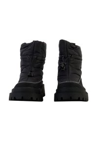 Botas de tobillo negras, acolchadas, con forma redondeada, superficie texturizada y suelas de goma negra con profundas ranuras y detalles de costura blanca.