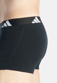 Svarta stretchiga bomullsboxershorts med en bred svart midjeband som har vita ränder och logotyp, slät yta och tajt passform.