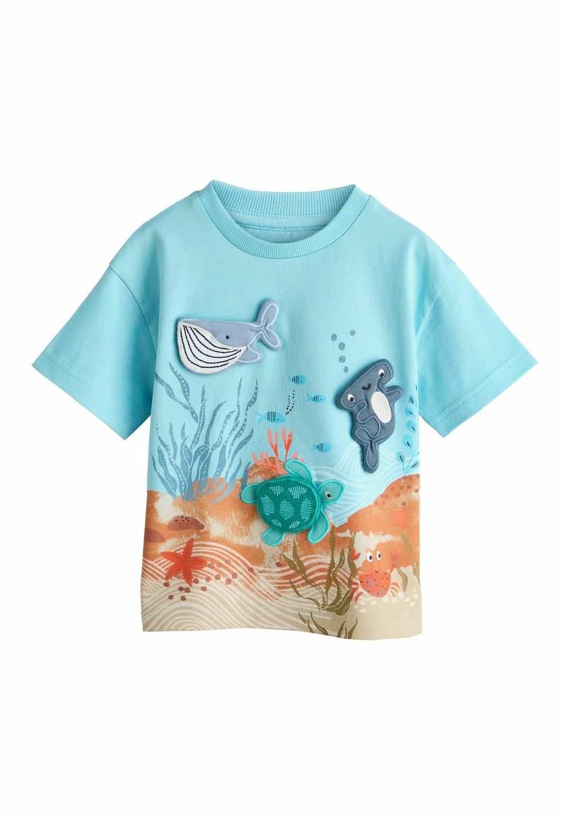 Svetlomodré tričko s krátkym rukávom so aplikáciami vodných zvierat: veľryba, korytnačka, ryba a krab na pozadí piesočného oceánskeho dna.