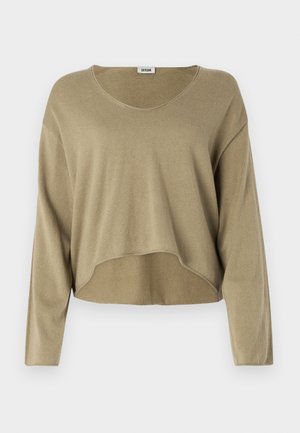 Lys beige avkortet genser laget av mykt strikket stoff. Har lange ermer, rund hals og en avslappet passform med en lett buet kant.