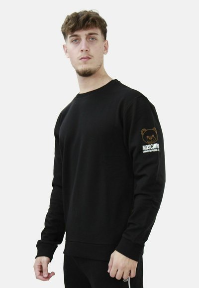 Felpa nera con collo rotondo, maniche lunghe e polsini a costine. Presenta un logo di un orso e la scritta "Moschino Underbear" sulla manica sinistra.