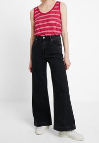 Röd och vit randig linne, kombinerad med högmidjade, vida svarta jeans. Outfit kompletterad med vita sneakers.