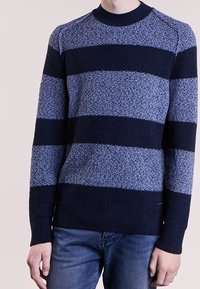 Marinblå och ljusblå randig tröja med en strukturerad stickad design, rund halsringning och ribbad mudd. Bärs över jeans.