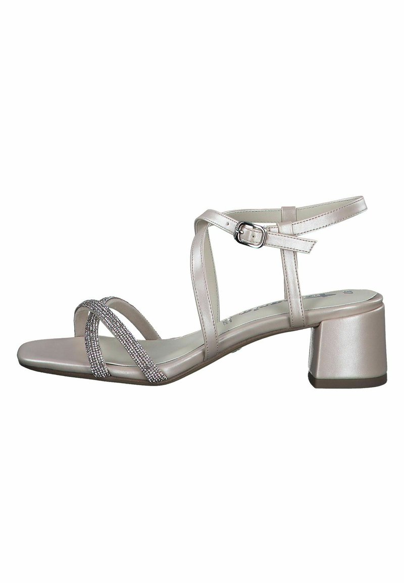 Vaaleanmetalli pinkki sandaali, jossa on ristiin menevät hihnat, strassikoristelu, säädettävä nilkkapanta ja paksu korko. Tasapohjainen muotoilu.