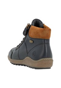 Bottine en cuir bleu foncé avec col en daim beige, surface texturée, fermeture éclair sur le côté et semelle en caoutchouc beige. Logo de la marque visible à l'extérieur.