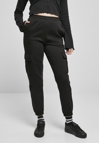 Svarta cargo sweatpants med elastisk midja, sidofickor och ribbade cuffs. Bärs med svarta sneakers och randiga strumpor.