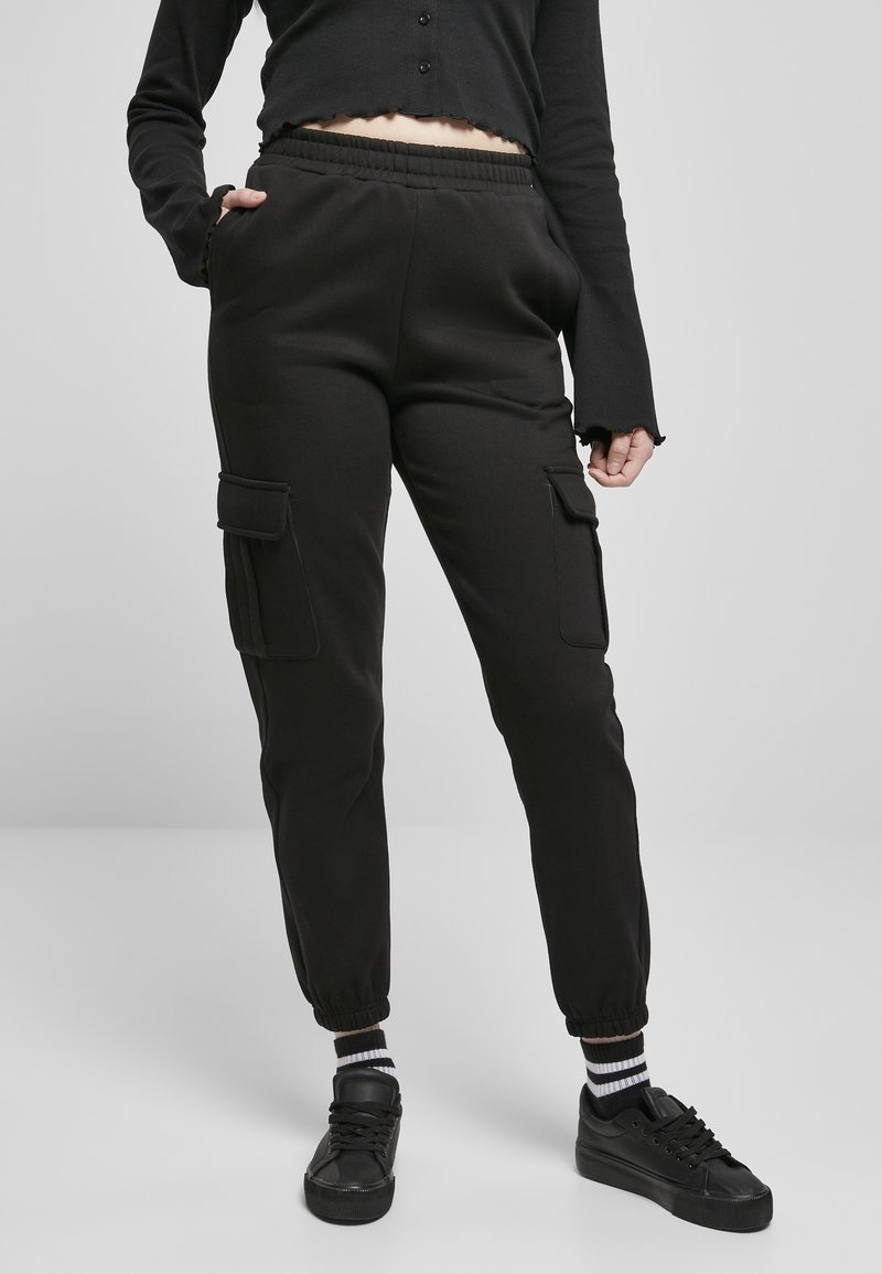 Svarta cargo sweatpants med elastisk midja, sidofickor och ribbade cuffs. Bärs med svarta sneakers och randiga strumpor.