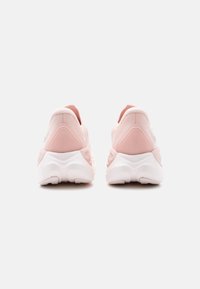 Ζευγάρι ανοιχτόροζ αθλητικά παπούτσια, εμφανιζόμενα από πίσω, με χοντρές λευκές σόλες και χαμηλό σχέδιο, σε απλό λευκό φόντο.