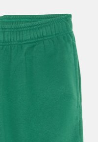Pantalons de survêtement en coton verts avec une taille élastique et une texture douce. Comprend des poches latérales et une coupe décontractée.