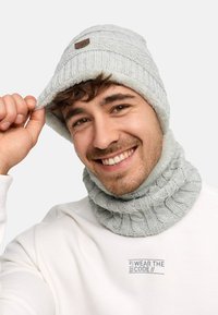 Gray knit beanie with a textured pattern and logo patch, paired with a matching cowl neck warmer. Soft, ribbed fabric; cozy design.