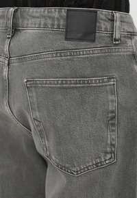 Pilki džinsai su lygiu paviršiumi, turintys užpakalinę kišenę ir juodą odinį etiketę su išspaustu užrašu "Selected".