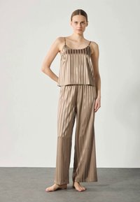 Setti öýjükli satin pyjamas, açyk yknjy zolaklary bilen. Üstüni düzetmek üçin spaghetti tutajyklary bar, we şal topary giň aýak görnüşinde.