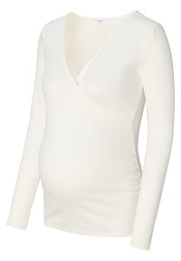 Langsleeve, witte zwangerschaps top van ribbeltextuur met een wikkeldesign, voorzien van een V-hals en zijruche voor een nauwsluitende pasvorm.