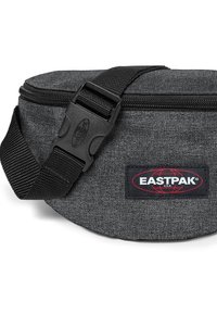Šedá látková ledvinka s zaobleným tvarem, která má zipové uzavření, nastavitelný černý pásek a červenou nášivku s logem Eastpak.