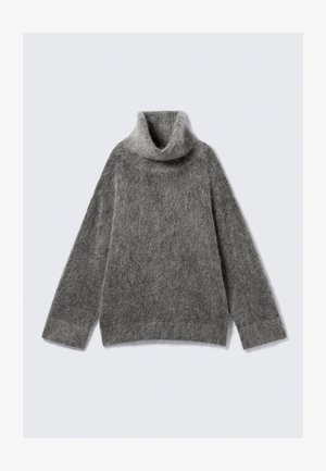 Suéter de cuello alto gris, hecho de un material de punto suave y aterciopelado. Presenta mangas largas, un ajuste holgado y un cuello ancho y doblado.