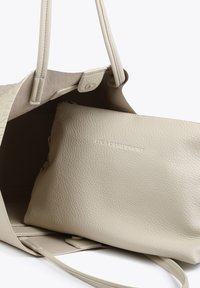 Beige läder tote väska med texturerad utsida, har långa handtag och tryckknappslås. Innehåller en slät, matchande zip-väska inuti.