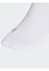 Calcetín deportivo blanco con superficie texturizada y logotipo verde en relieve. Presenta una forma de calcetín tradicional con talón y puntera reforzados.