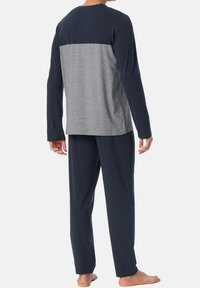 Completo loungewear da uomo composto da una maglia a maniche lunghe blu navy e grigia con un design a blocchi di colore e pantaloni abbinati blu navy in tessuto morbido.