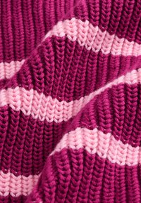 Gros plan d'un tissu tricoté épais avec des rayures horizontales alternées en rose foncé et rose clair.