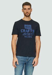 Navyblauwe katoenen t-shirt met een blauwe grafische print met de tekst "ARTS & CRAFTS SERVICE AND SUPPLIES," ronde hals, korte mouwen.