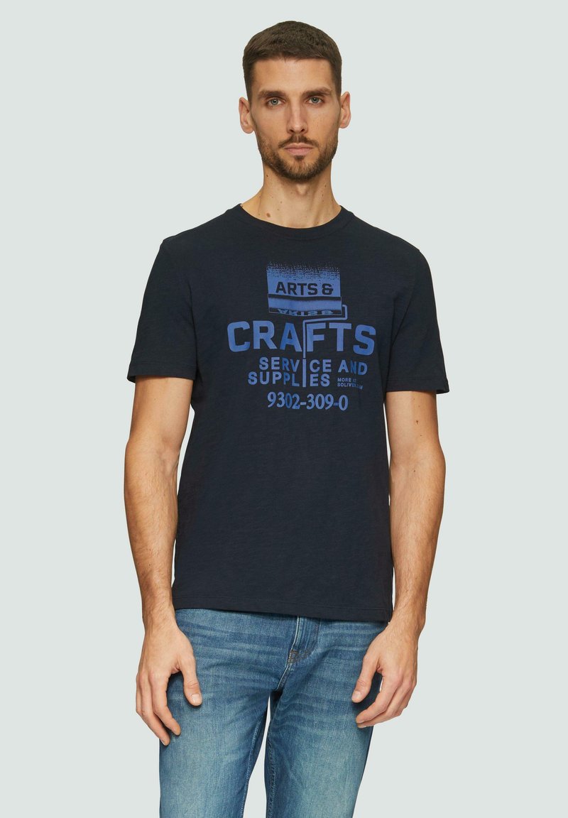 Navyblauwe katoenen t-shirt met een blauwe grafische print met de tekst "ARTS & CRAFTS SERVICE AND SUPPLIES," ronde hals, korte mouwen.