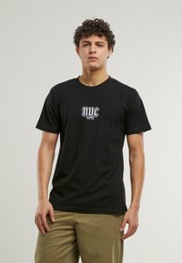 Svart bomull T-skjorte med en hvit "nyc" logo på brystet. Korte ermer, rund hals og avslappet passform. Teksturert stoff.