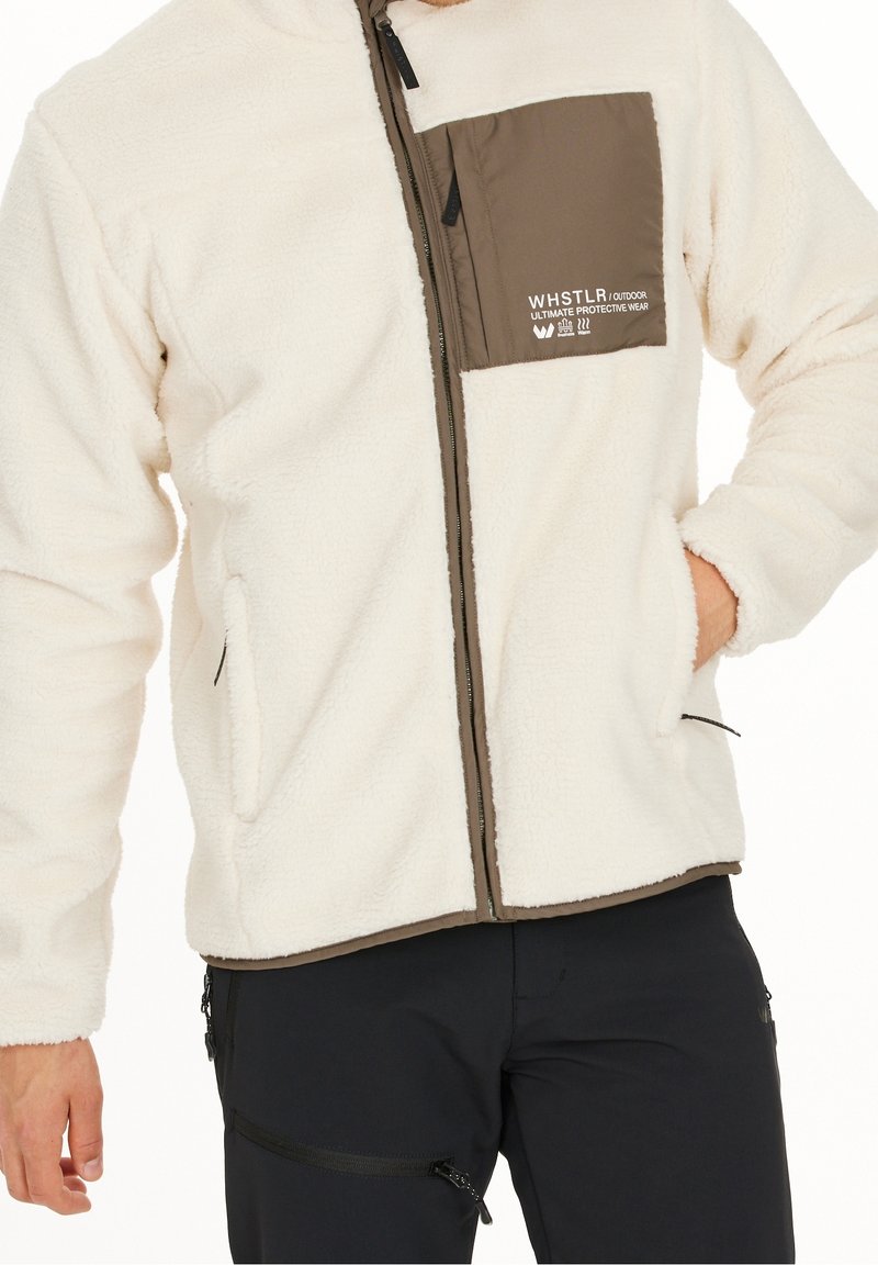 Giacca in pile di colore bianco sporco con tasca sul petto con zip marrone, dotata di tasche laterali e tessuto testurizzato per calore e comfort.