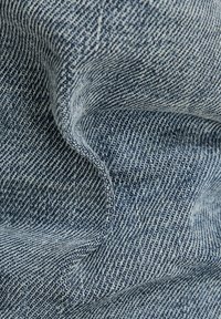 Tejido de mezclilla en un tono azul con una superficie texturada. Presenta patrones de tejido visibles y sutiles variaciones de color en toda su extensión.