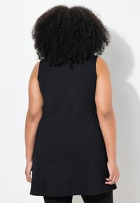 Svart ärmlös tunika med rund nederkant, gjord av mjukt tyg. Har en lös passform och en slät textur, lämplig för avslappnad användning.