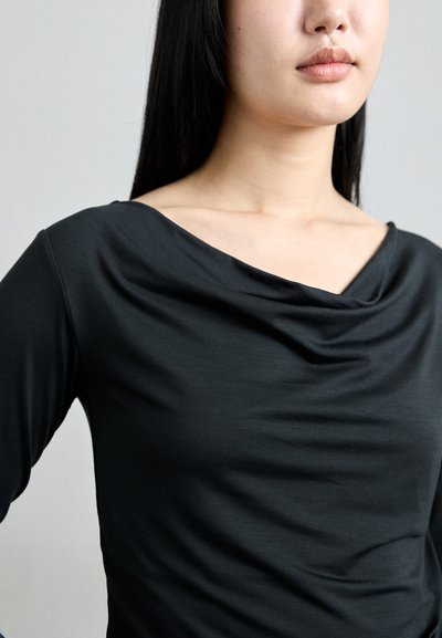 Black long-sleeve top featuring a draped, cowl neckline. The fabric appears smooth and stretchy, highlighting the shoulder and collarbone area.