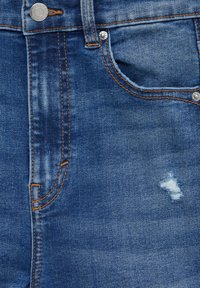 Denim jeans in dark blue with a faded look, featuring orange stitching, a front pocket, and a small distressed area near the pocket.