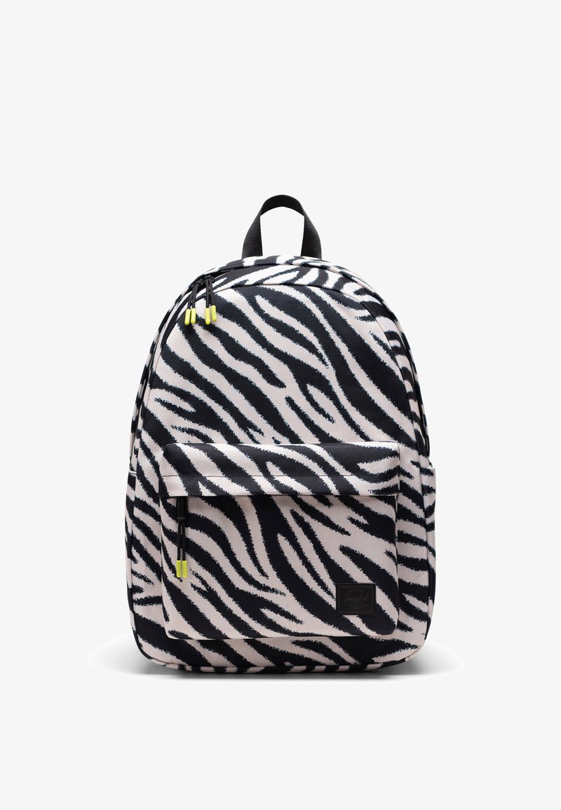 Sac à dos avec des rayures zébrées noires et blanches, poche avant zippée, poignée noire et tirettes de fermeture éclair à embouts jaunes sur fond blanc.