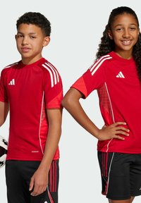 Rode sportieve shirts met witte accenten en strepen, gecombineerd met zwarte shorts met rode streepdetails. De stof ziet er glad en lichtgewicht uit.