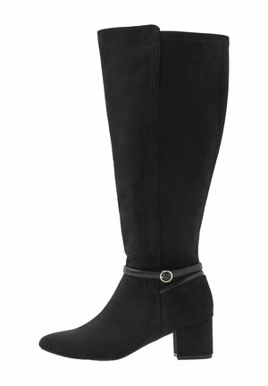 Botte noire en suède montant jusqu'au genou, avec talon bloc et fine bride à la cheville ornée d'une petite boucle métallique ronde sur fond blanc.