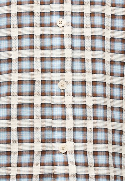 Tissu à carreaux beiges, bruns et bleus avec des lignes horizontales et verticales cousues, et quatre boutons beiges alignés au centre.