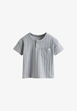 Szürke, rövid ujjú póló bordázott textúrával, kerek nyakkivágással és egy mellzsebből álló részlettel, amelyen egy apró logó és fa gomb található.