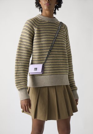 Gestreifter Strickpullover in Beige und Oliv mit einem gerippten Rundhalsausschnitt. Kombiniert mit einem plissierten khakifarbenen Rock und einer kleinen lila Umhängetasche.