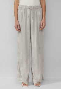 Lichtgrijze, wijde broek met verticale crème strepen, elastische tailleband, trekkoorddetail en een zachte textuur. In combinatie met lichtgekleurde sandalen.