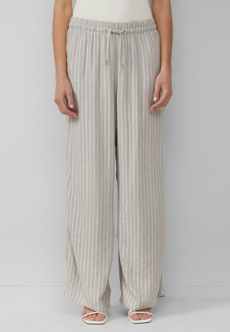 Lichtgrijze, wijde broek met verticale crème strepen, elastische tailleband, trekkoorddetail en een zachte textuur. In combinatie met lichtgekleurde sandalen.