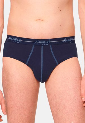 Male torso wearing navy blue Sloggi briefs with contrast stitching on a plain light background.