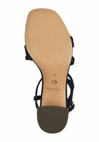 Sandal nera con cinturini, dotata di una suola beige liscia, presenta una battistrada in gomma testurizzata, una cinghia alla caviglia regolabile e il logo del designer impresso sulla suola.