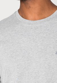 Grijs katoenen T-shirt met een ronde hals, voorzien van een klein geborduurd logo in marineblauw, met een gladde textuur en middelzwaar materiaal.