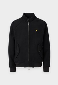 Svart fleece-jakke med glidelås, med høy krage, to sidelommer, ribbestrikkede mansjetter og en liten gul logo på brystet.