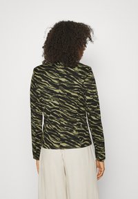Chaqueta de patrón de cebra en negro y verde oliva, con mangas largas y un diseño ajustado, hecha de una tela texturizada. Vista trasera simple.