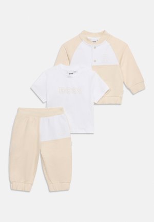 Set de haine pentru bebeluși din trei piese, cu blocuri de culoare bej și alb, incluzând pantaloni, tricou cu mânecă scurtă cu textul "BOSS" și jachetă cu nasturi.