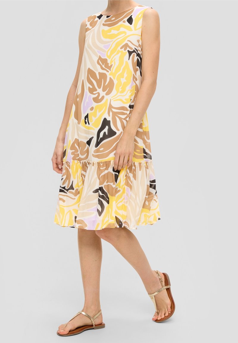 Robe sans manches avec une base jaune clair ornée de motifs floraux abstraits en brun, noir et lavande ; design fluide avec un ourlet à volants.
