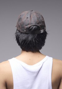 Șapcă neagră cu modele marmorizate roșii, material din bumbac, curea reglabilă în spate și un mic accent metalic în partea din spate.