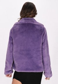 Giacca in pelliccia sintetica viola con collo a camicia e maniche lunghe, caratterizzata da una texture morbida e una vestibilità comoda. La vista posteriore mostra cuciture lisce.
